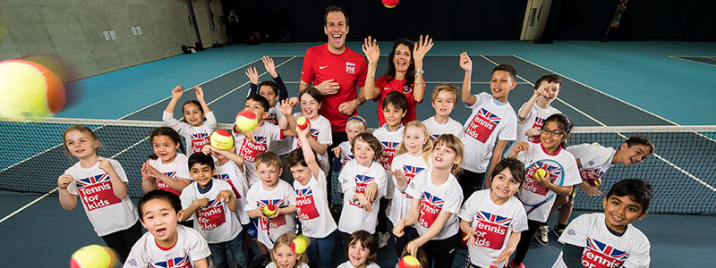 Large group of kids with tennis balls on a tennis court