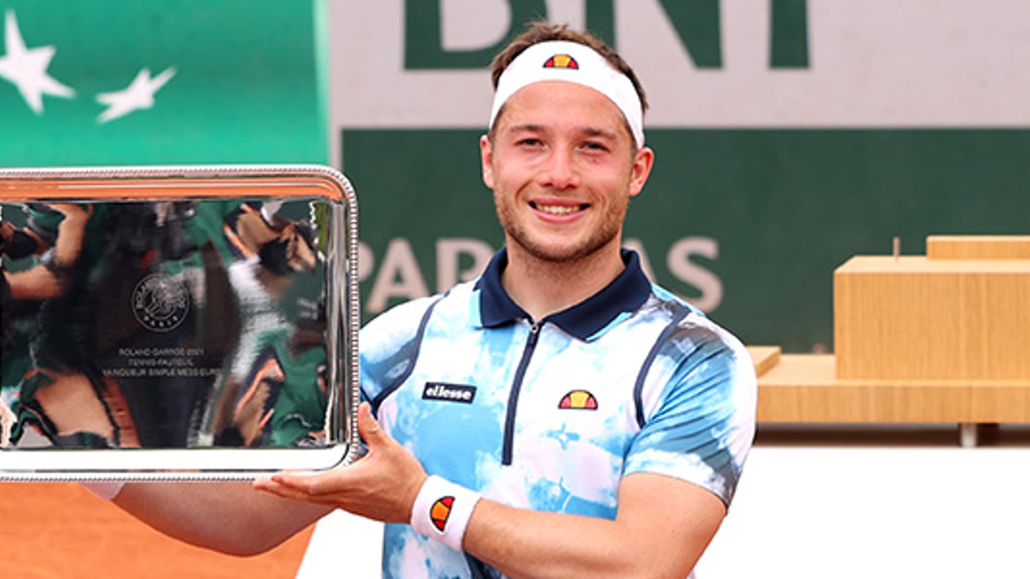 Alfie Hewett holding a trophy on a tennis court