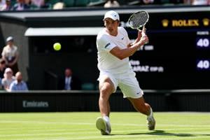 Oliver Tarvet wearing white and leaning in to hit a drop shot on Centre Court at Wimbledon