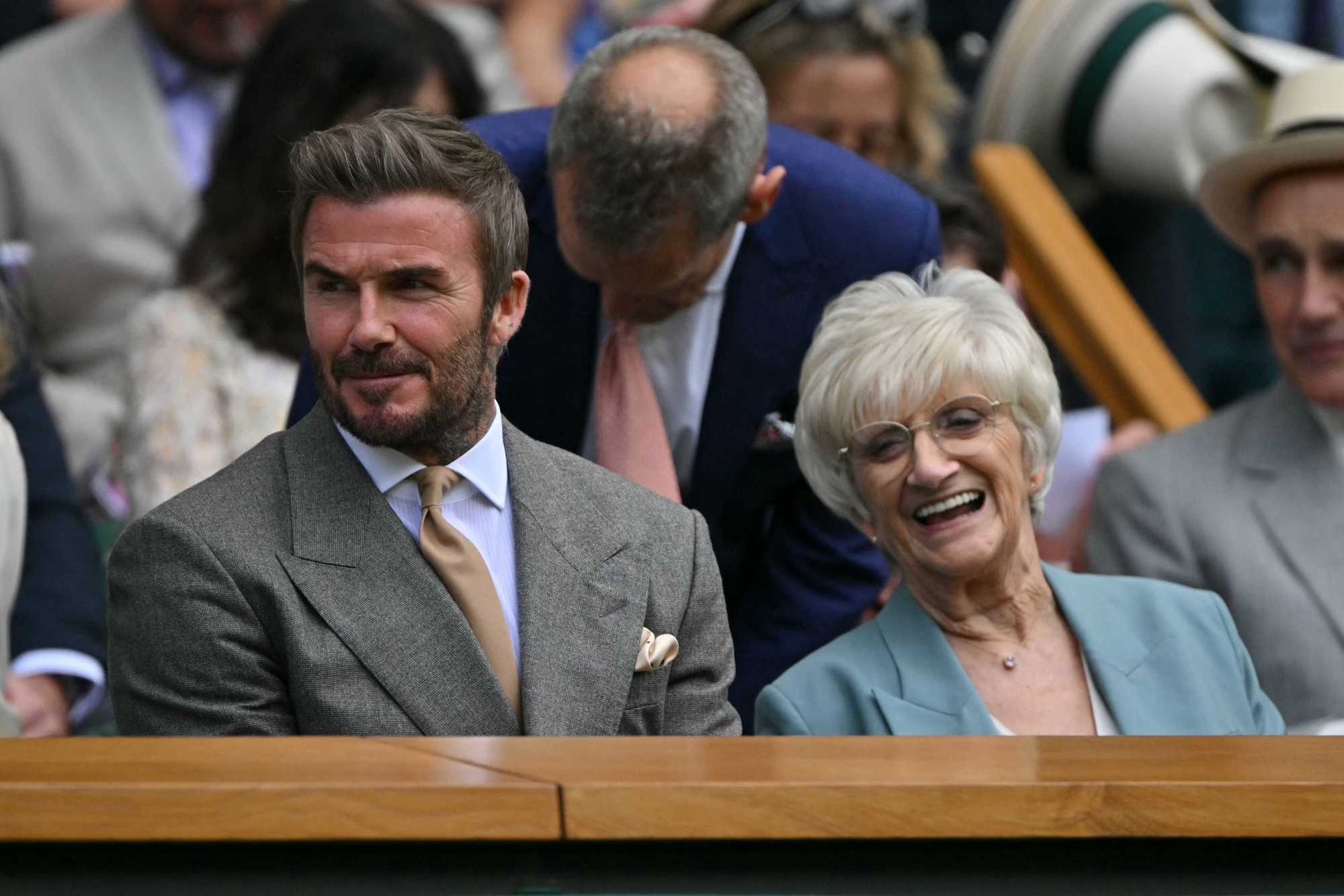 Sir David Beckham smiling alongside his mum Sandra in the Royal Box on Centre Court