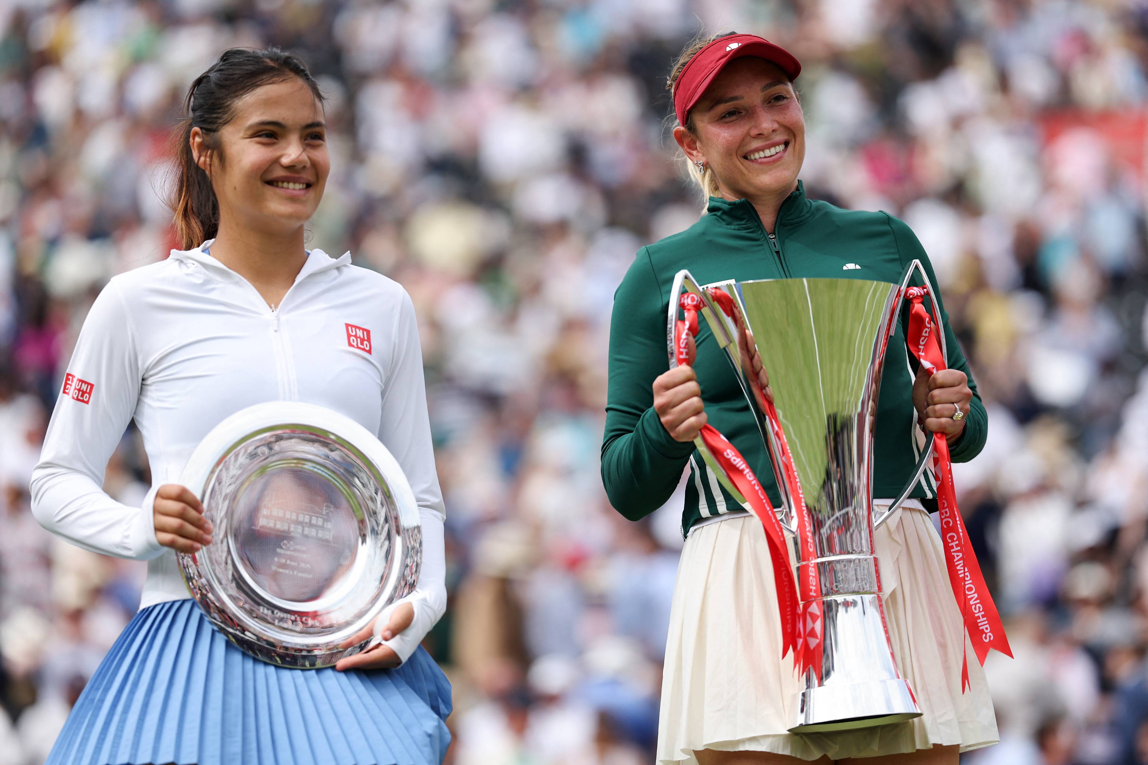Donna Vekic smiling while holding the HSBC Championships trophy alongside runner-up Emma Raducanu