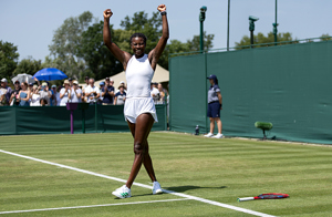 British tennis player Esther Adeshina smiling and lifting her arms up in the air on court at Wimbledon qualifying 