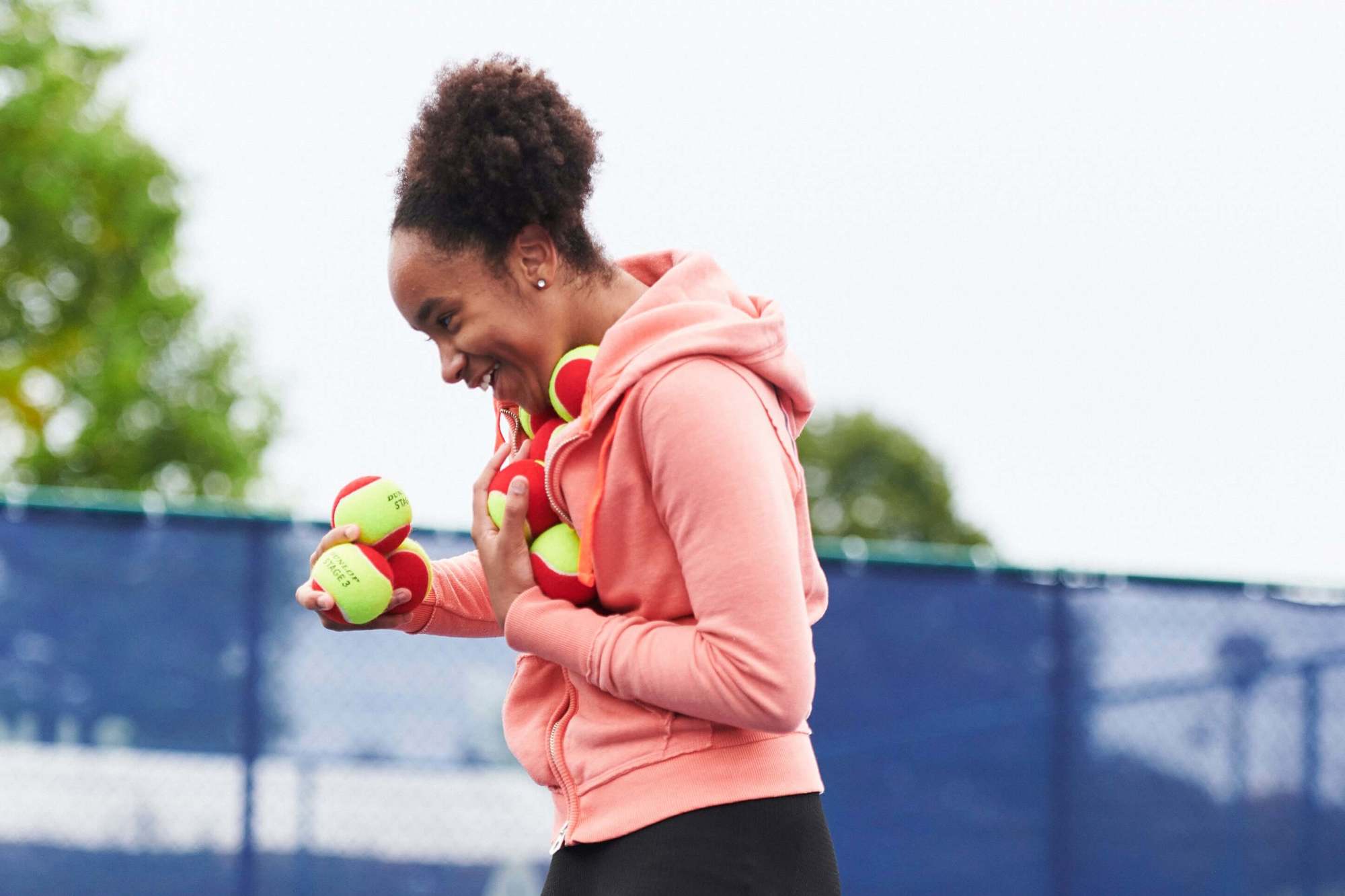 Girl carrying tennis balls and laughing